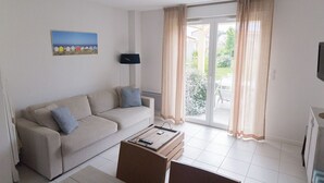Una sala de estar con sofá, una mesa de centro, un cuadro y un ventanal corredizo al exterior.