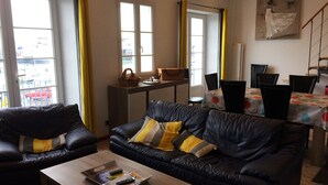 Ein Wohnzimmer mit einer schwarzen Ledersofa, einem Holztisch und einem Essbereich mit Tisch und Stühlen.
