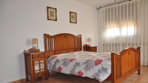 Un dormitorio con una cama de madera, dos mesitas de noche y una ventana con cortinas.