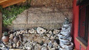 Una pared de piedra rústica con techo de madera y una pared roja a la derecha.