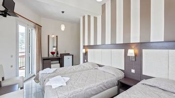Habitación de hotel con cama, mesitas de noche, escritorio, silla, televisión y ventana con cortinas.