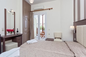 Habitación de hotel con cama, escritorio con espejo, silla, lámpara y vistas al exterior.