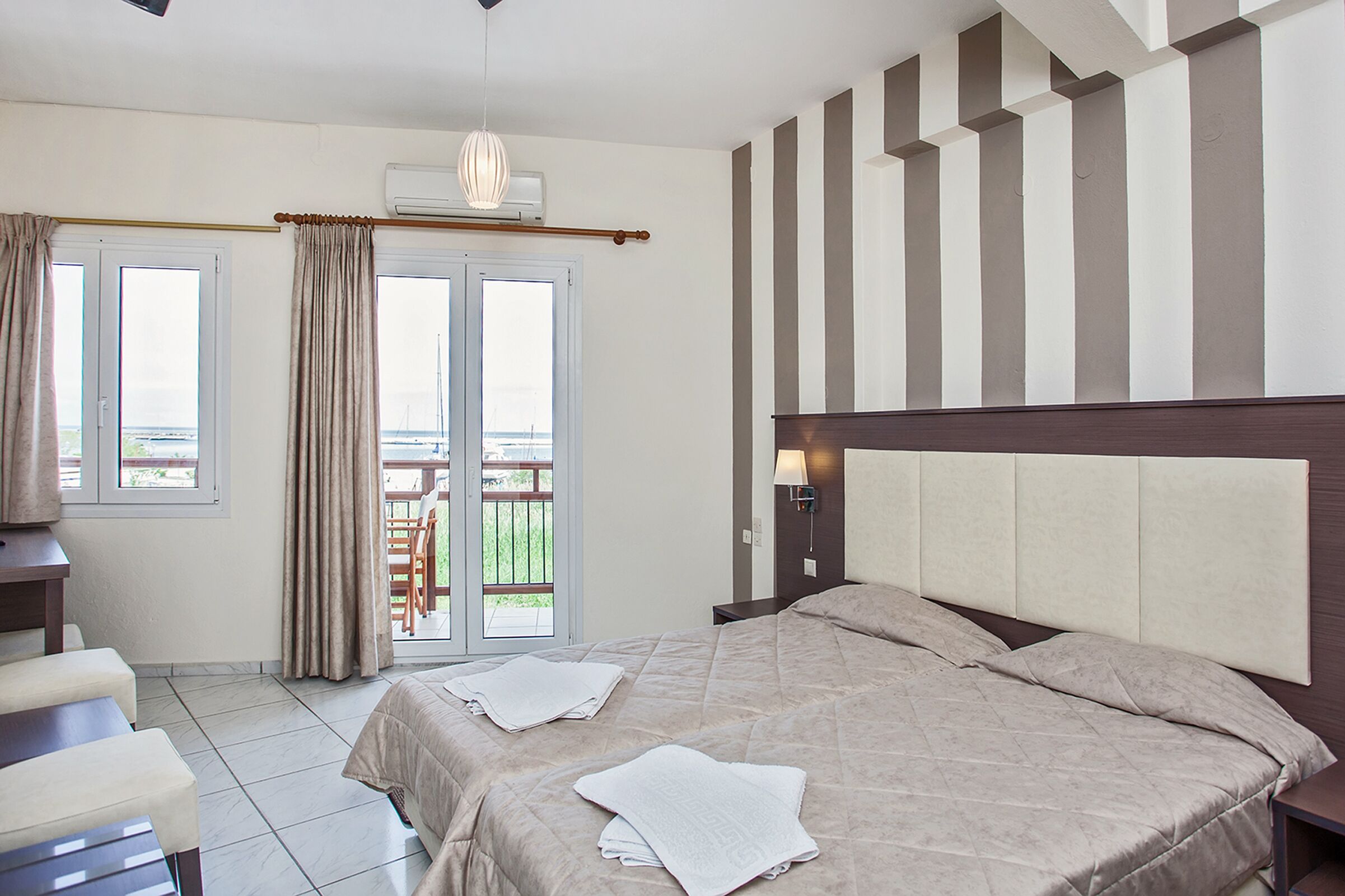 Un dormitorio con cama, escritorio y vistas a un espacio exterior por una puerta.