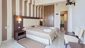 A hotel room with a large bed, bedside tables, a desk, and a chair.