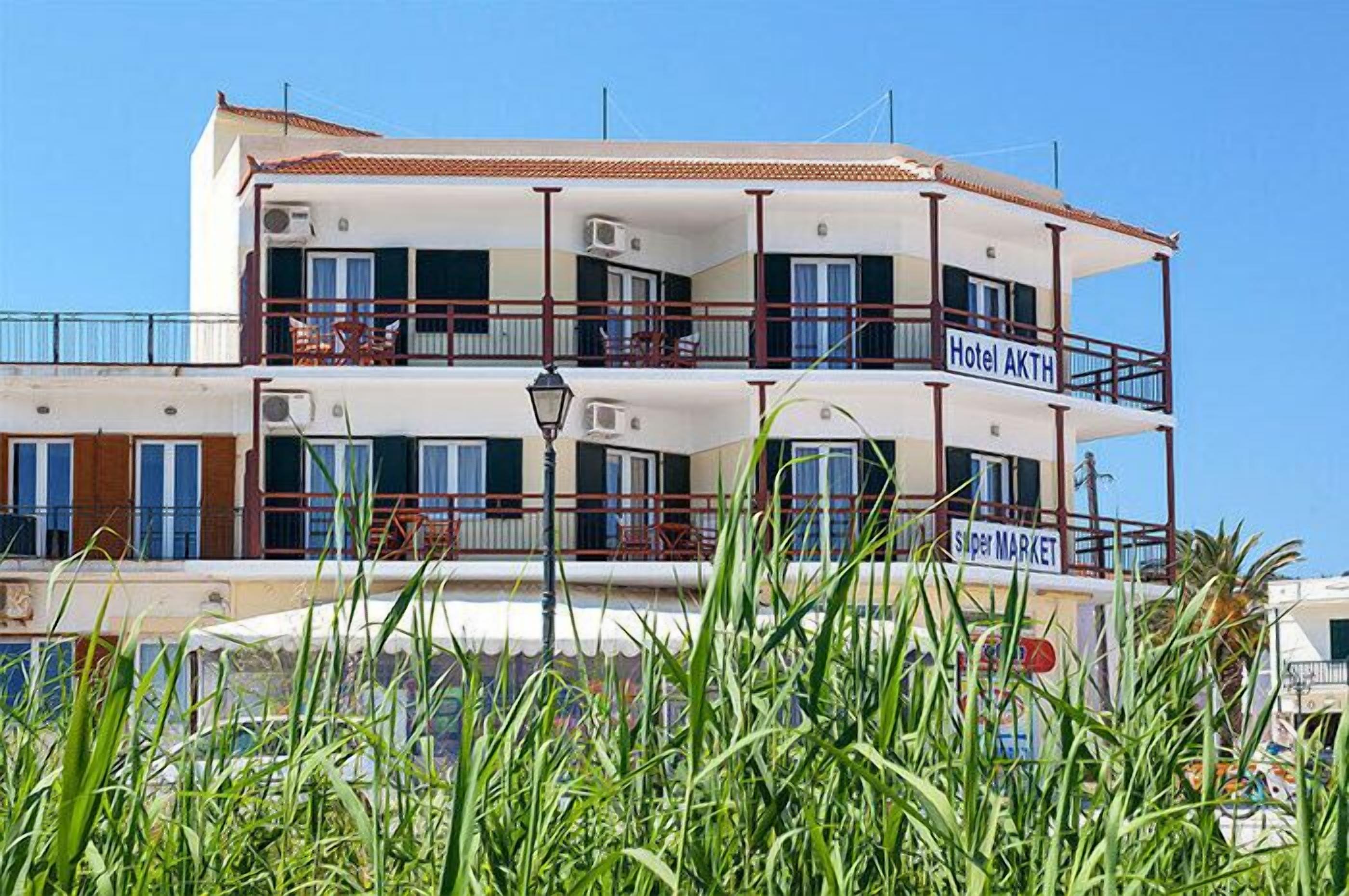 Un hotel de varios pisos con balcones, un cartel que dice 'Hotel AKTH' y un cartel que indica 'Super Market'.