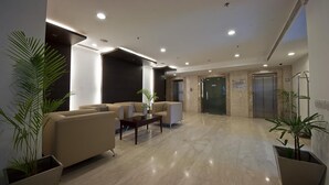 A modern lobby with a reception area, seating, and an elevator. - Hotel Grenville (Gurugram)
