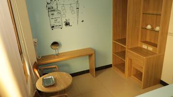 Una habitación con un banco de madera, una pequeña mesa redonda, un espejo y una pared decorada con motivos de viaje.