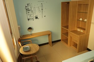 Una habitación con un banco de madera, una pequeña mesa redonda, un espejo y una pared decorada con motivos de viaje.