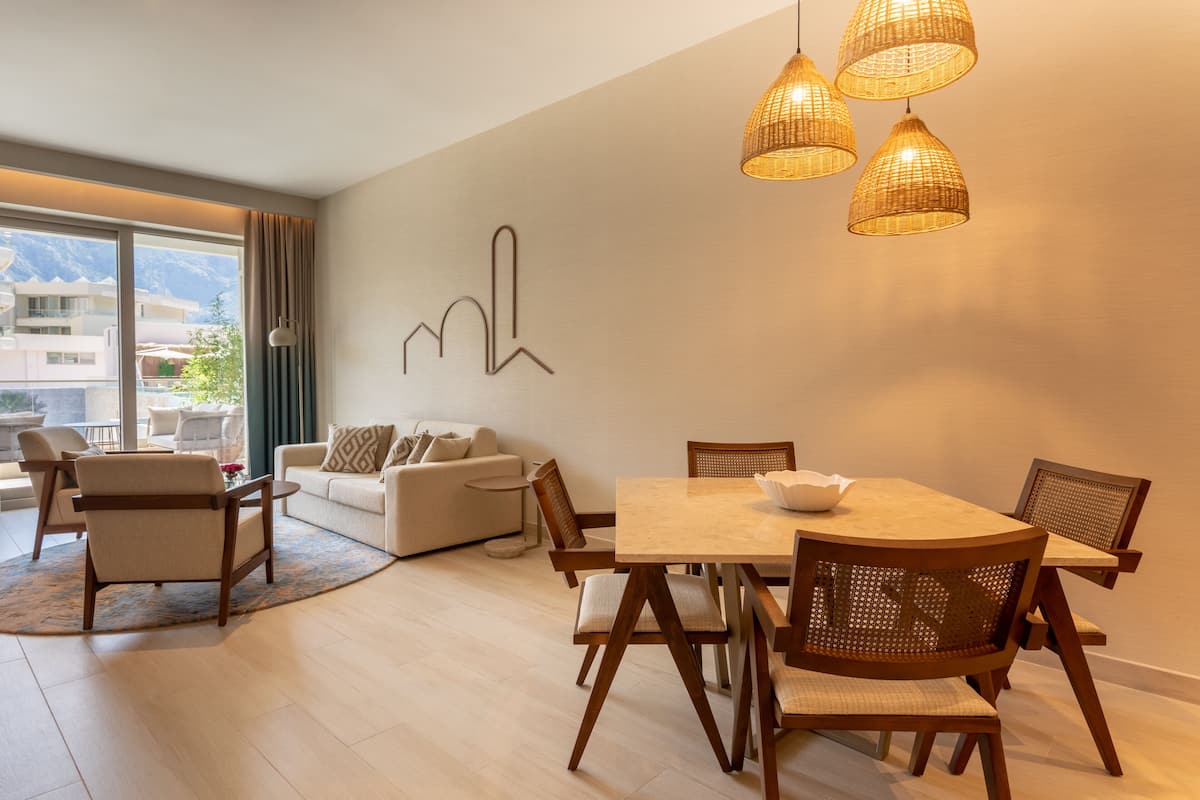 Un salon moderne avec un coin repas, comprenant un canapé, des fauteuils, une table et une œuvre d’art murale représentant un paysage urbain.