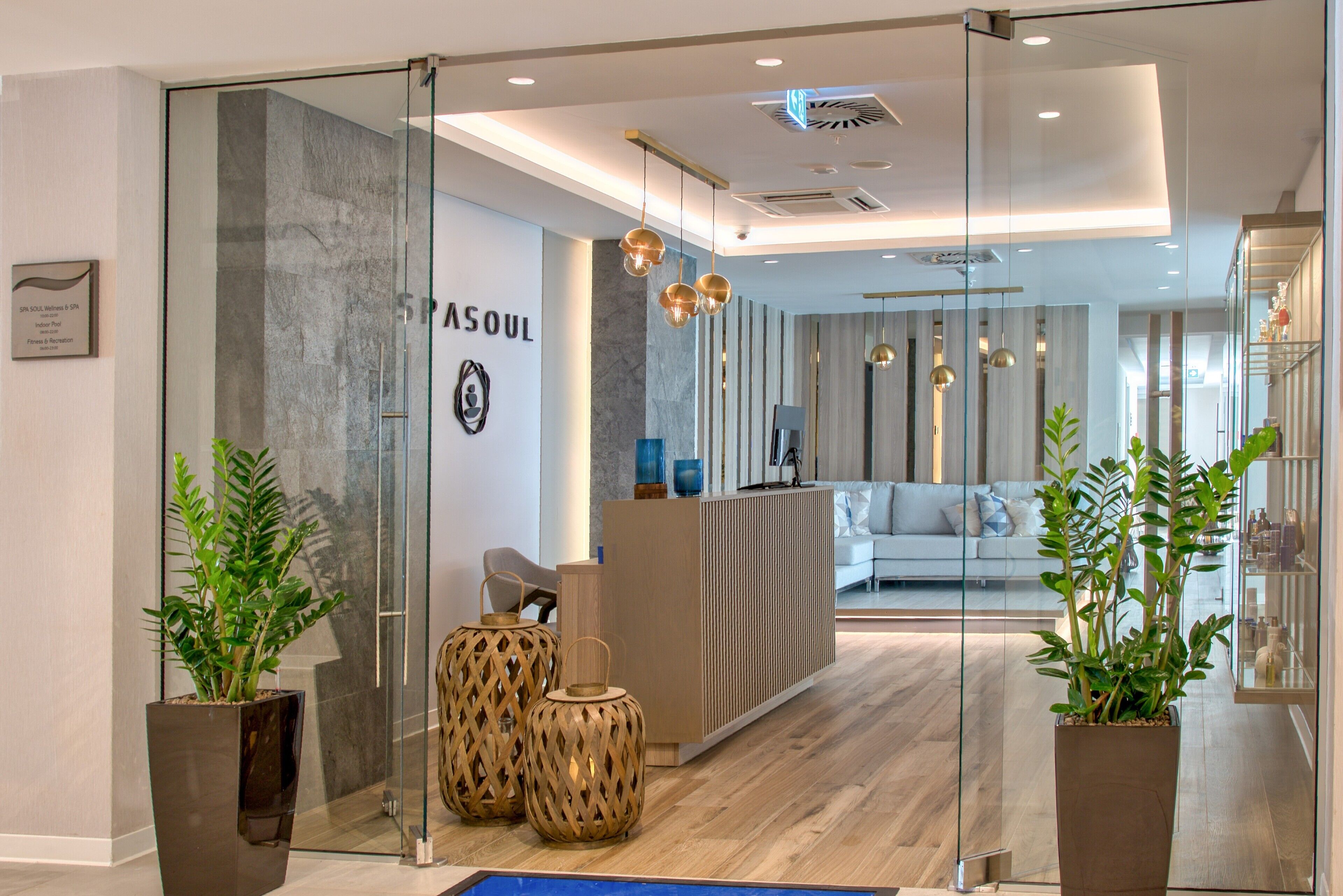 Un espace d’accueil moderne avec une cloison en verre, un comptoir d’accueil et des plantes en pot.