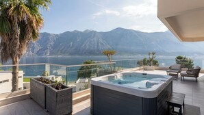 A modern outdoor hot tub area with a mountain view, seating, and planters.