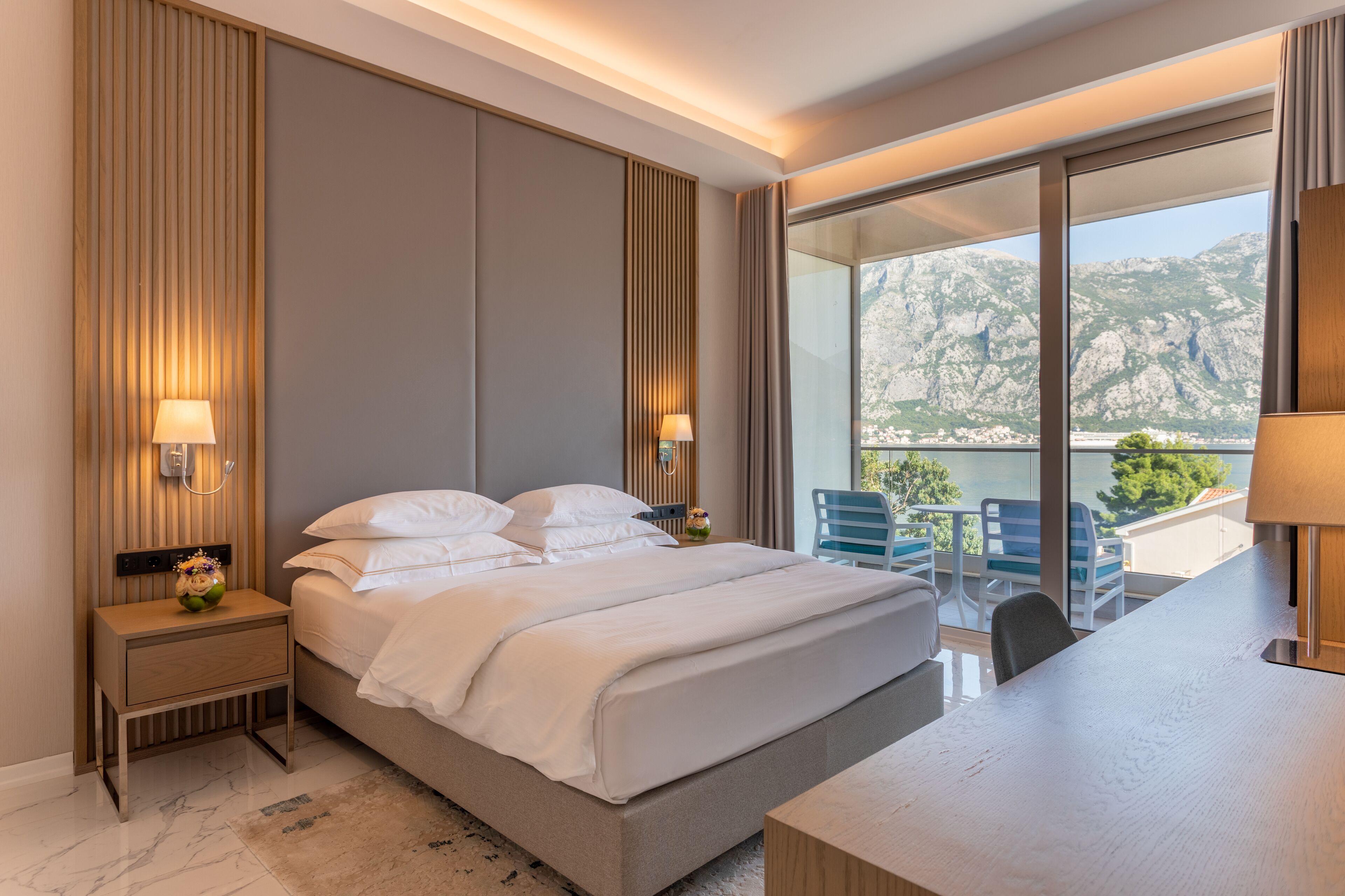 Un hotel moderno con una cama grande, lámparas de noche, una mesita de noche y vistas a las montañas a través de amplias ventanas.