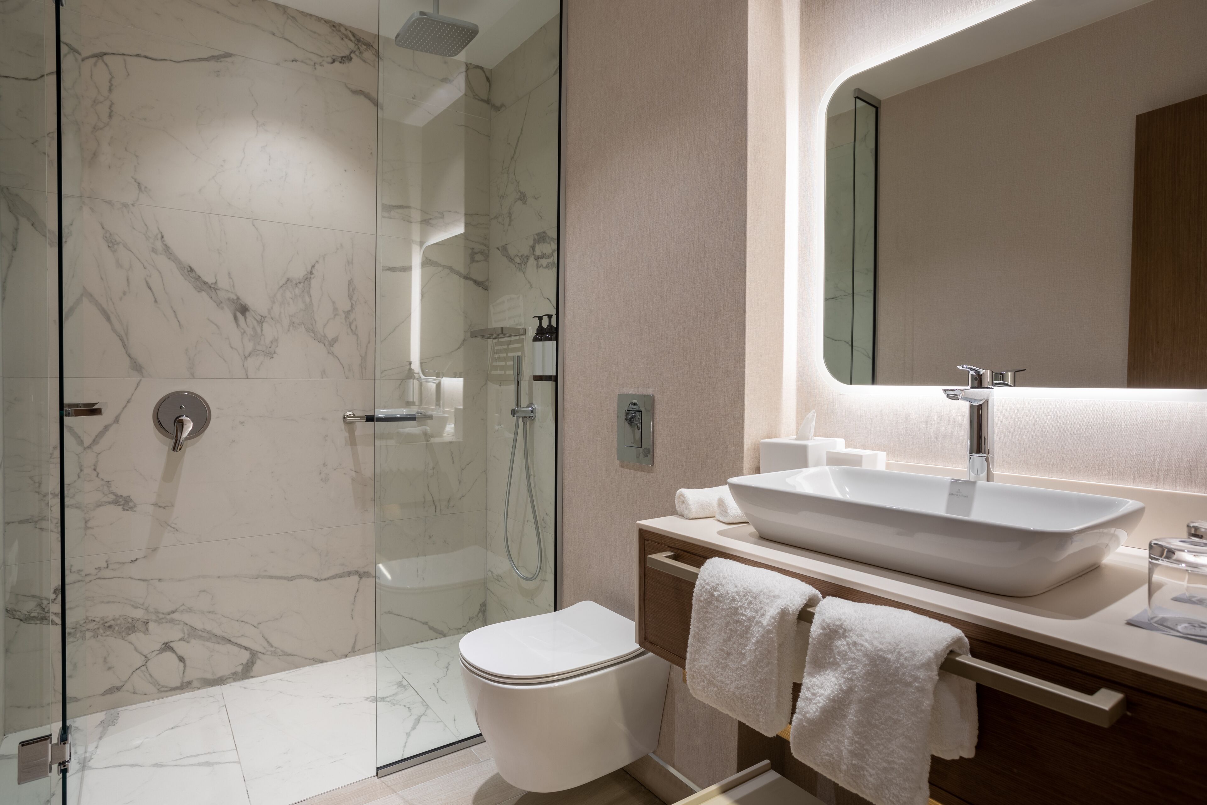 A modern bathroom with a glass-enclosed shower, a white sink, and a large mirror.