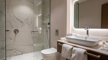 A modern bathroom with a glass-enclosed shower, a white sink, and a large mirror.