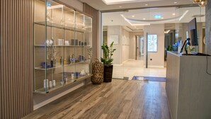 Un moderno vestíbulo de hotel con una vitrina de vidrio, suelo de madera y un mostrador de recepción.