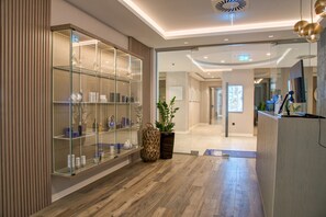 Un moderno vestíbulo de hotel con una vitrina de vidrio, suelo de madera y un mostrador de recepción.