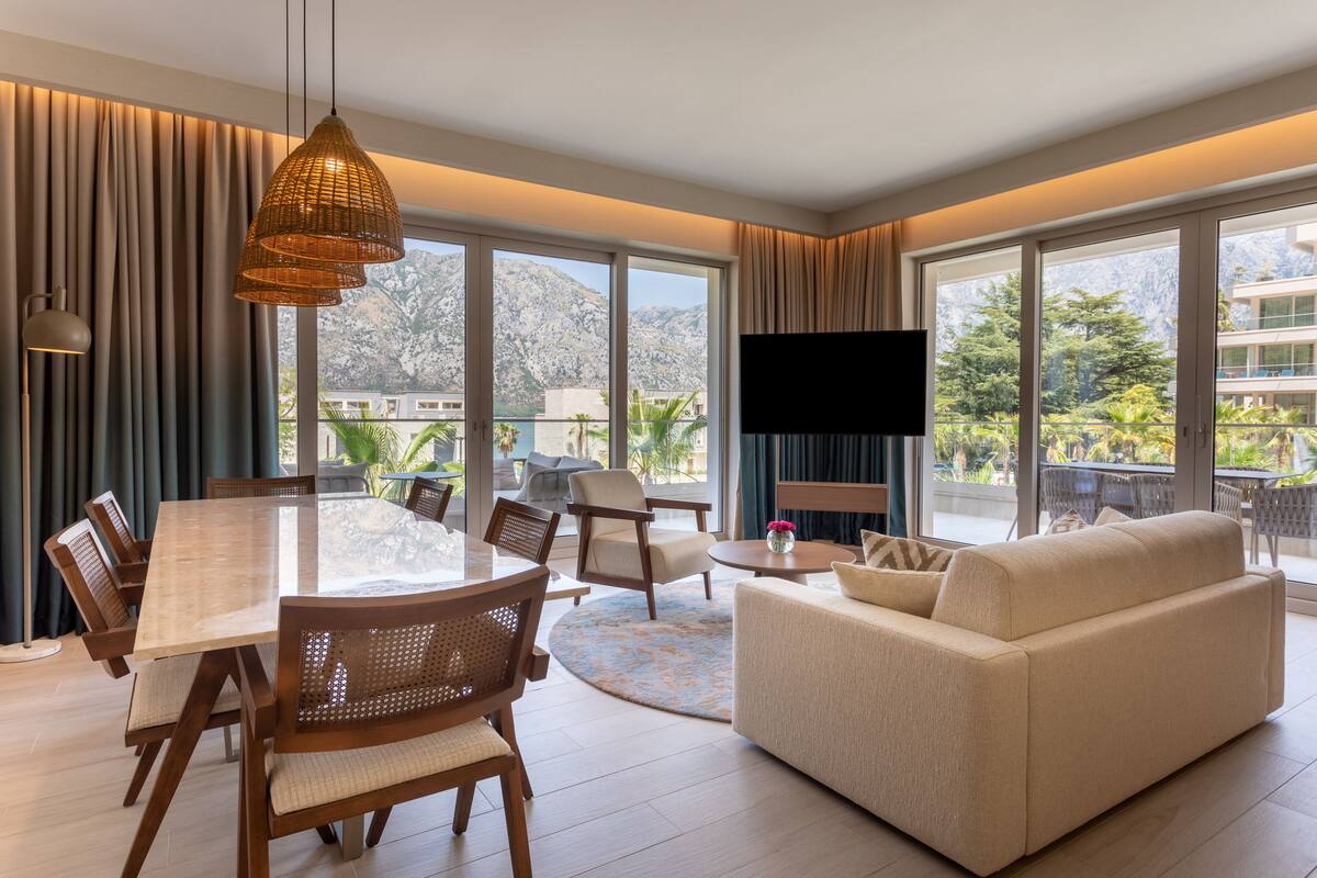 Un vaste espace de vie comprenant une table à manger, des canapés et une grande fenêtre donnant sur une vue imprenable sur les montagnes.