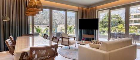 A spacious living area with a dining table, sofas, and a large window offering a mountain view.