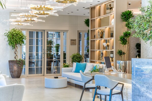 Una sala de estar moderna con un sofá, sillones, una mesa de centro y una estantería.
