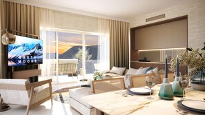 Een moderne hotelkamer met een grote televisie waarop 'EARTH MOODS' staat, een bank, een eettafel gedekt voor twee personen en uitzicht op bergen.