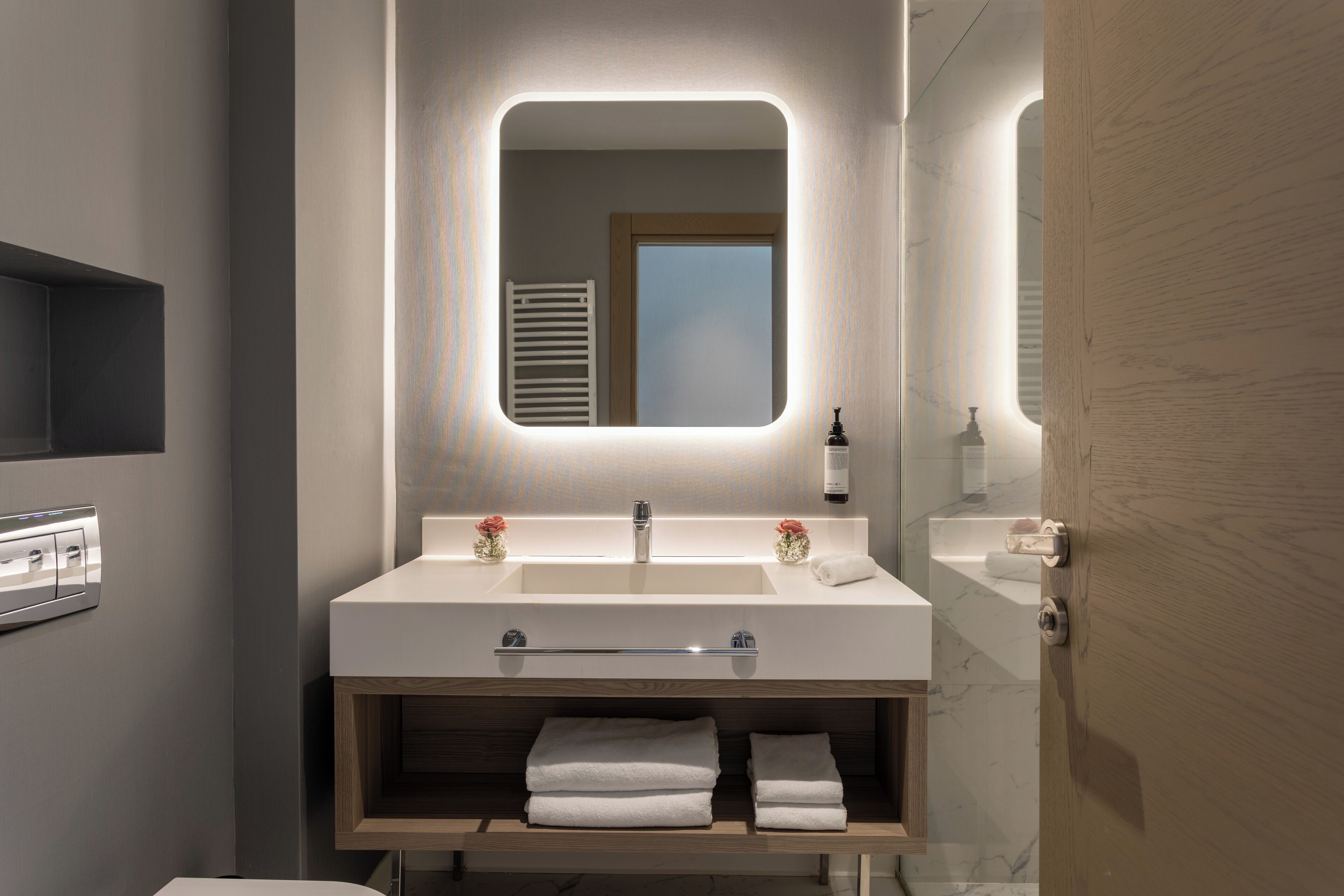 Un baño moderno con un espejo grande, lavamanos dobles y un mueble de tocador de madera.