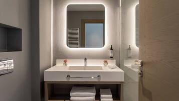 Un baño moderno con un espejo grande, lavamanos dobles y un mueble de tocador de madera.