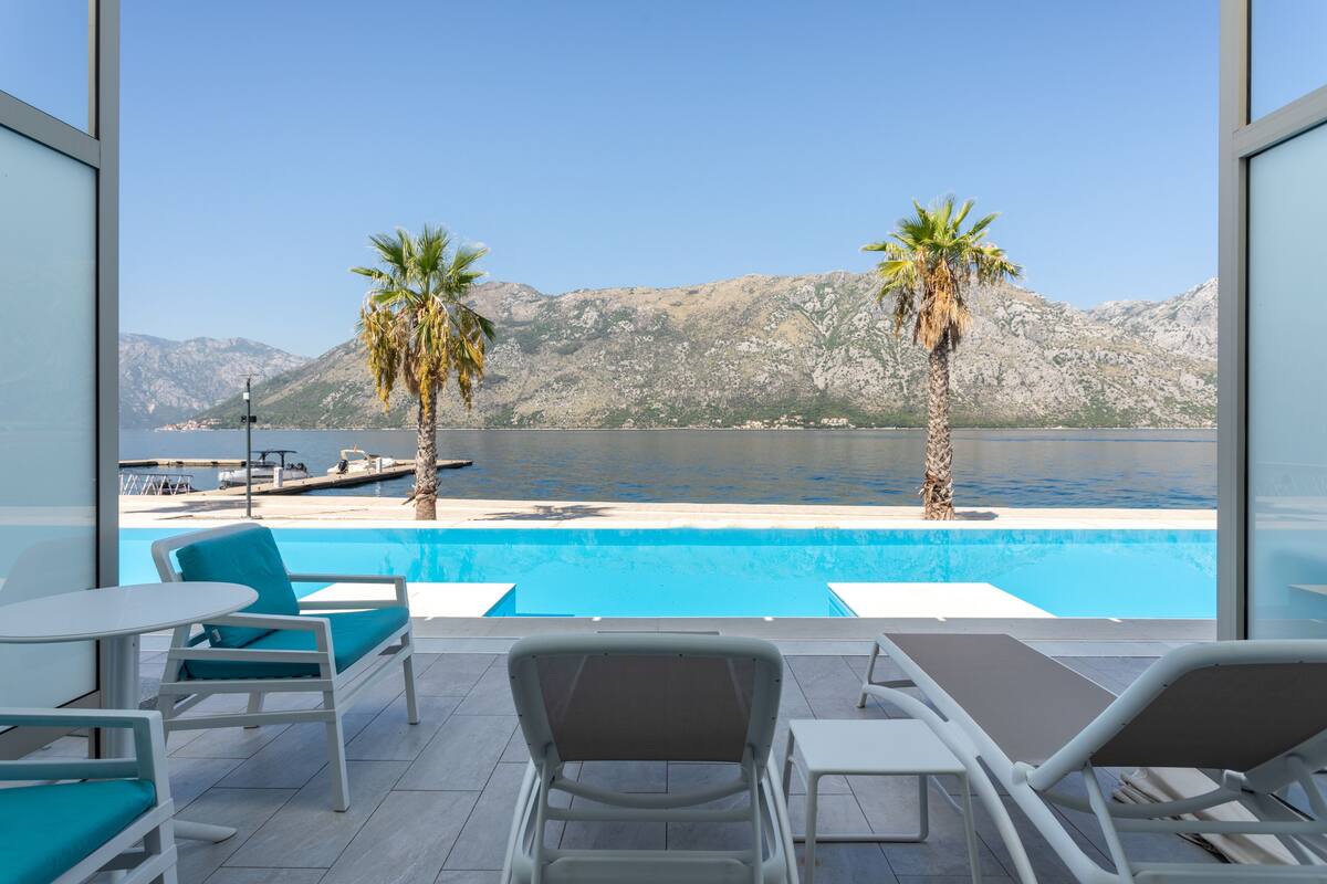 Un espace aménagé au bord de la piscine, avec des chaises longues et une vue sur un lac et des montagnes.