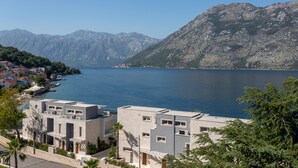 Un pueblo costero con edificios modernos, una vista despejada del mar y montañas al fondo.
