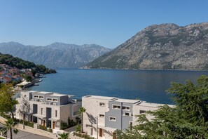 Un pueblo costero con edificios modernos, una vista despejada del mar y montañas al fondo.