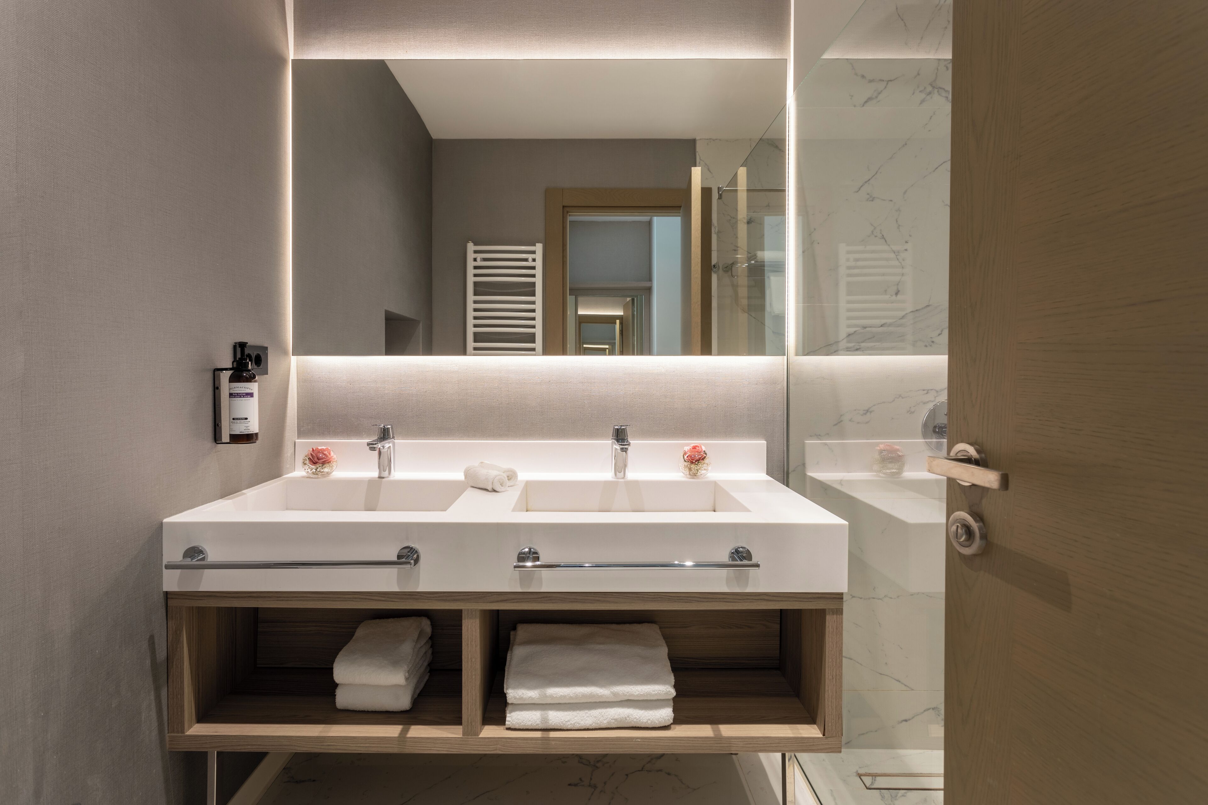 A modern bathroom with a double sink, a mirror, and a towel rack.