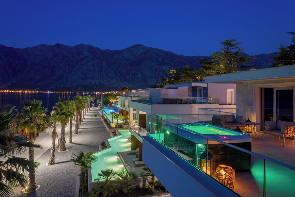 Un hotel moderno con piscina, asientos al aire libre y vistas a la montaña.