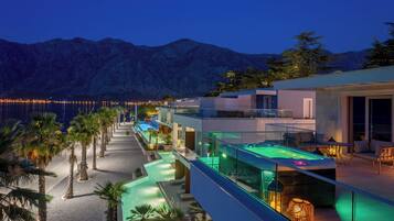 A modern hotel with a pool, outdoor seating, and mountain views.