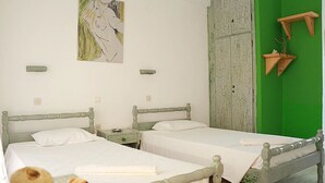 A room with two beds, a green wall, and a rustic wooden wardrobe. - Gongis Studios (Corfu)