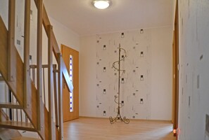 Een kamer met een houten trap, een staande lamp en behang met een patroon.