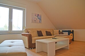 A living room with a sofa, a white coffee table, and a painting on the wall. - Apartment Wiesenblick - Apartment (Schenkendöbern)