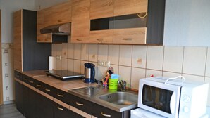 A modern kitchen with wooden cabinets, a stainless steel sink, a microwave, and a coffee maker.