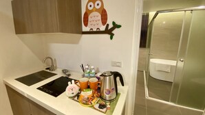 A compact kitchen with a sink, a kettle, and a coffee maker. There is a small cabinet above the counter and a wall decoration of an owl. - He Yi B&B (Luodong)