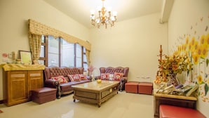 A living room with a sofa set, a coffee table, a wooden cabinet, and a vase with flowers. - He Yi B&B (Luodong)
