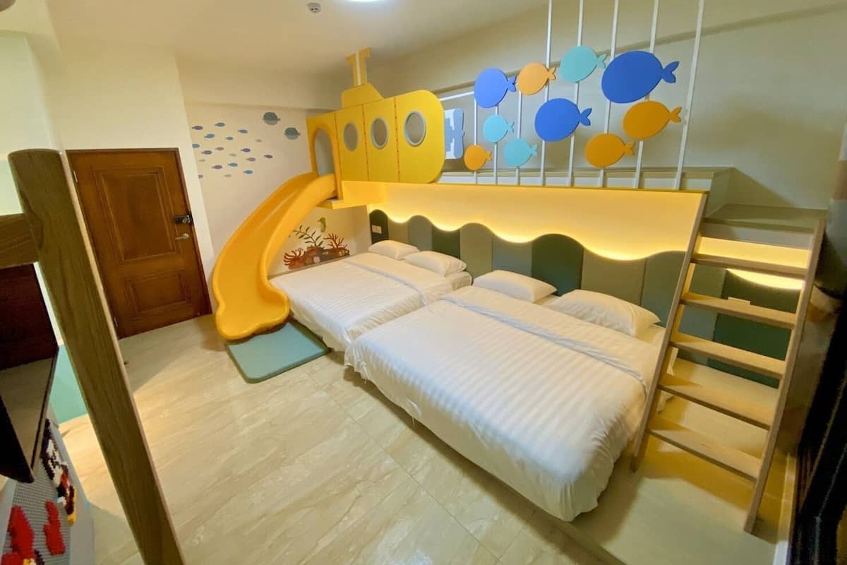 A children's room with a bunk bed, a slide, and a wall decorated with fish.