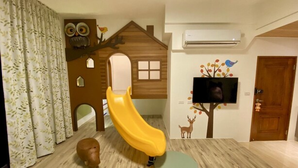 A children's play area with a slide, a small animal figure, and a television on the wall. - He Yi B&B (Luodong)