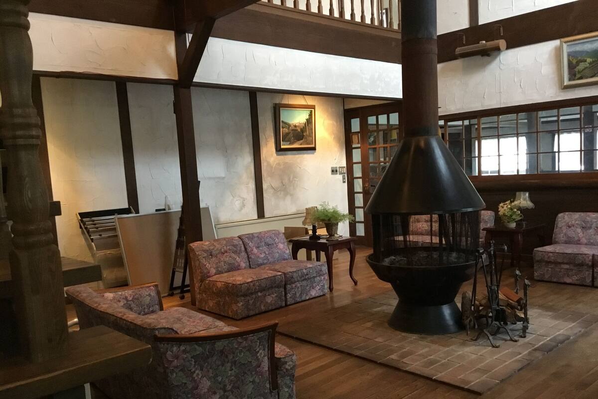 Un interior acogedor con chimenea, sofás de estampado floral, suelo de madera y un cuadro en la pared.