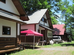 Ein zweistöckiges Gebäude mit rotem Dach, einer Holzterrasse und einem roten Sonnenschirm.