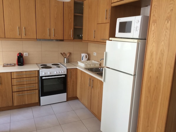 A kitchen with wooden cabinets, a stove, a microwave, and a refrigerator.
