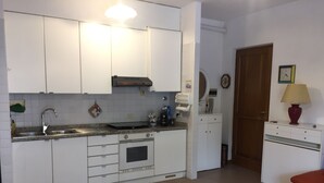 A compact kitchen with white cabinets, a stainless steel sink, and a built-in oven. - Casa Matilde (Massa)
