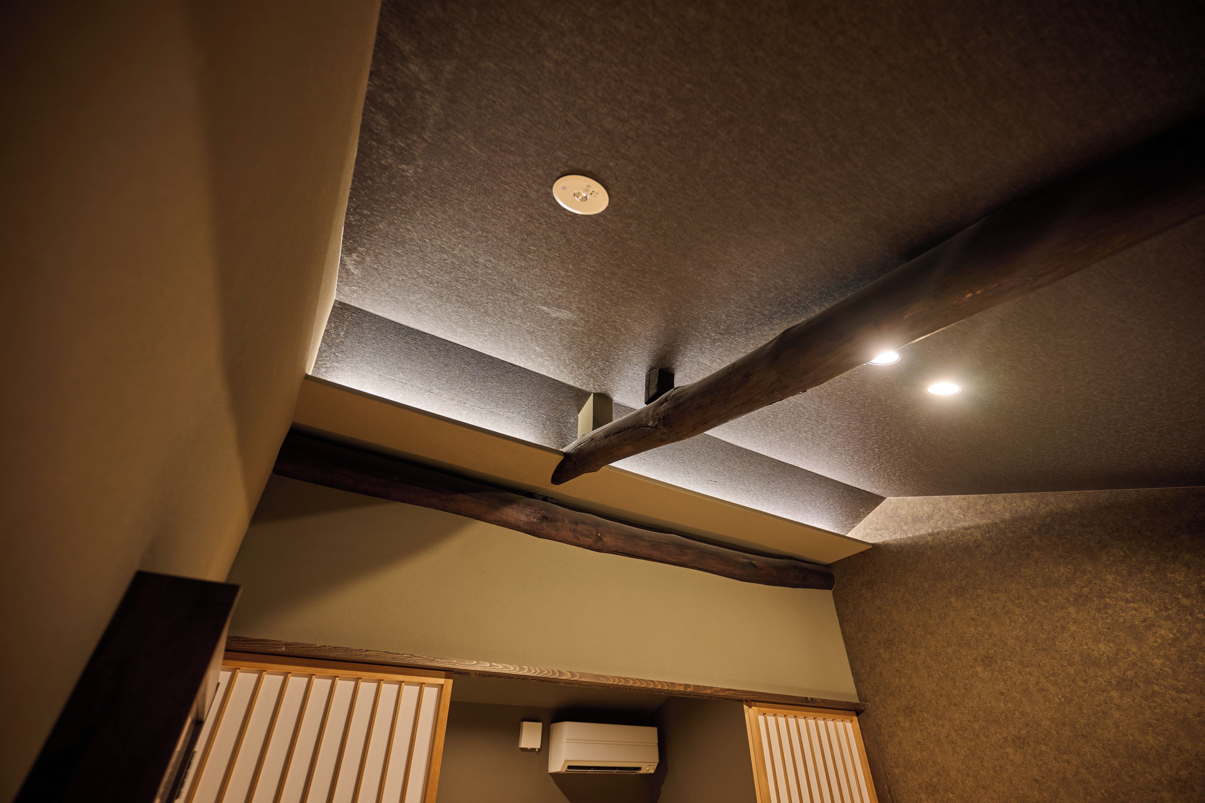 Een plafond met inbouwspots en een zichtbare airconditioning.