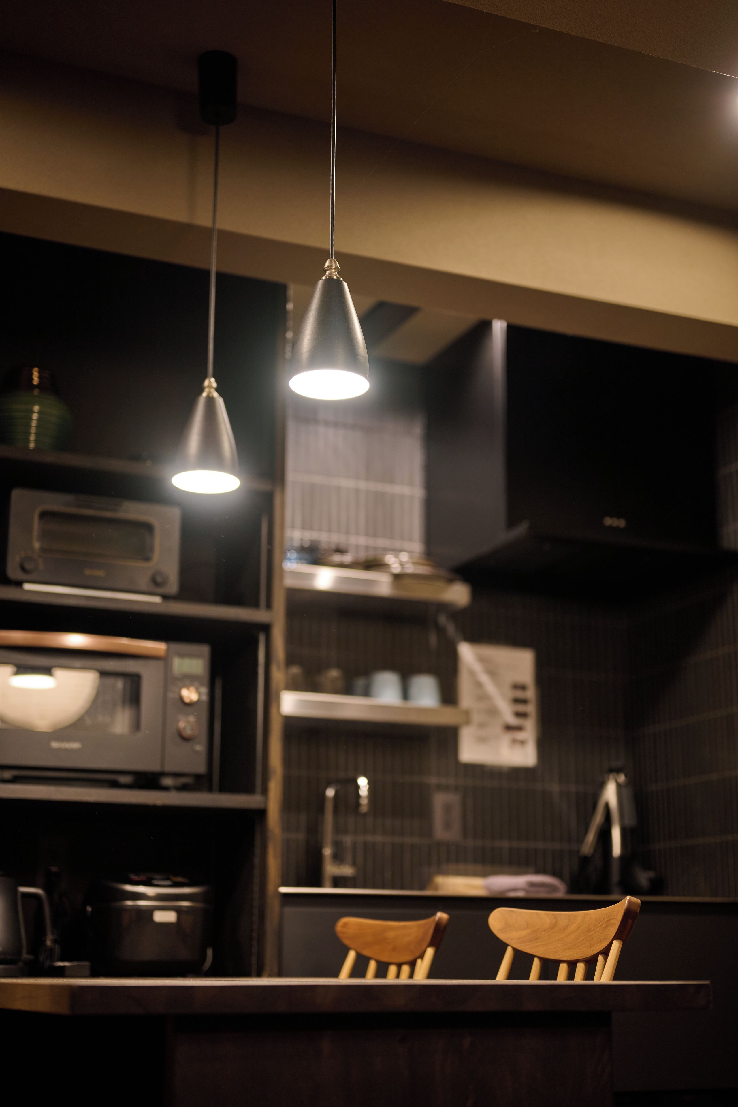 A kitchen with a microwave, oven, and two wooden chairs.