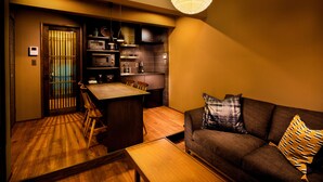 A compact living space with a dining area, kitchenette, and a sofa with patterned cushions. - SKY Kyoto (Kyoto)