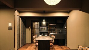 A modern dining area with a wooden table and chairs, a built-in microwave, and a hanging light fixture. - SKY Kyoto (Kyoto)