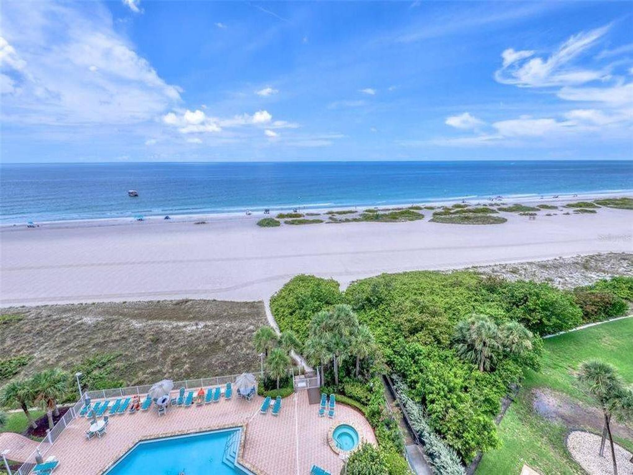 Un resort con piscina, sillas de descanso y vista a la playa.