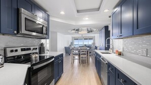 Una cocina moderna con armarios azul oscuro, electrodomésticos de acero inoxidable y vistas al área de estar.